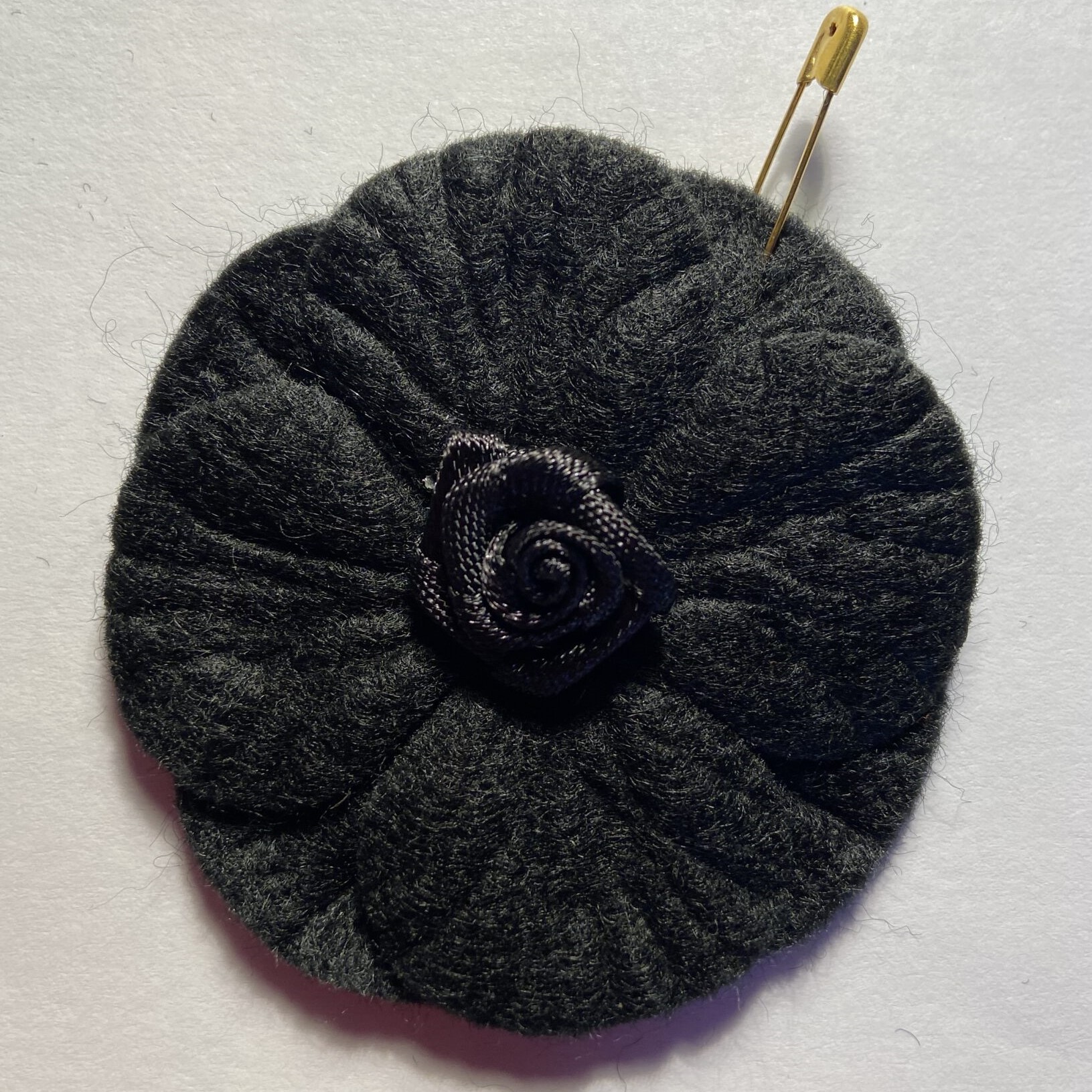 A black fabric poppy with a rose design at the centre