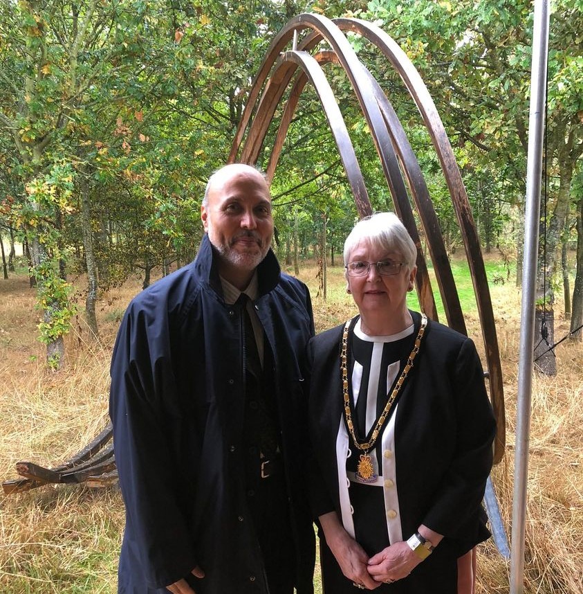 A man and a woman stand in front of an abstract sculpture