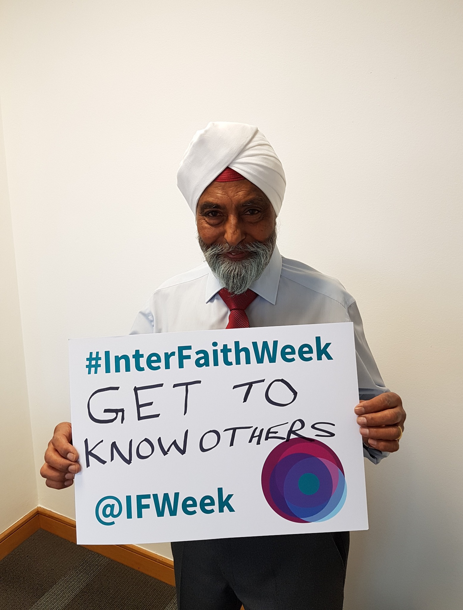 Photo of a Sikh man holding a card that reads 'Get to know others'