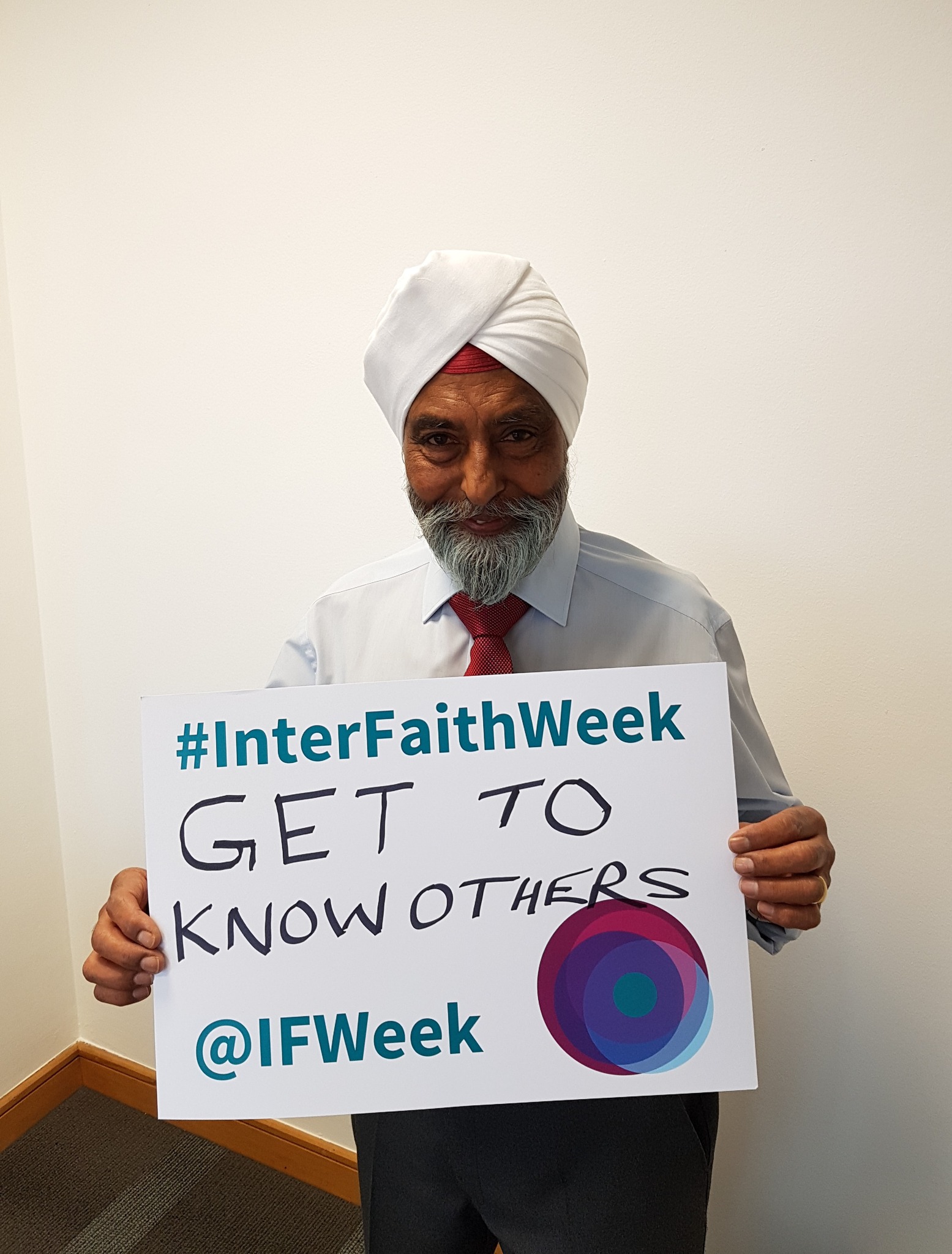 Photo of a Sikh man holding a card that reads 'Get to know others'