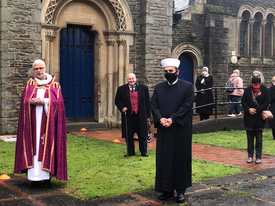 People stand socially distanced in front of a church