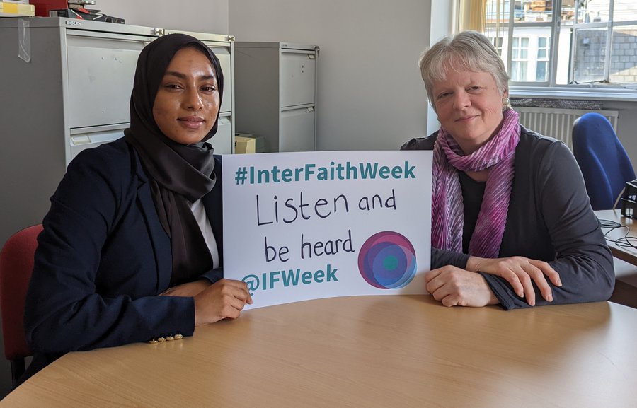 Two people holding a card that says 'Listen and be heard'